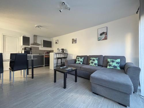 un salon avec un canapé et une table dans l'établissement La brise marine apt rdc maison cour fermée parking et terrasse à 800 m plage Omaha beach avec table de ping pong proche Port en Bessin, à Vierville-sur-Mer