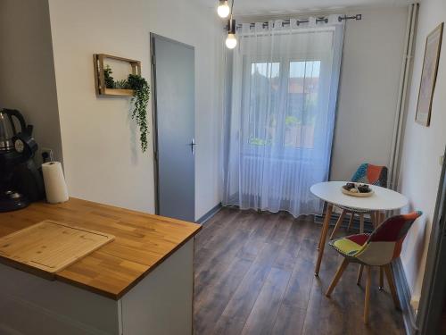 une cuisine avec une table et une petite table avec des chaises dans l'établissement Le Maupré au Coeur d'Arbois, à Arbois