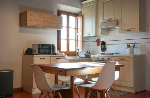a kitchen with a wooden table and white chairs at Olive Tree Apartment in Impruneta