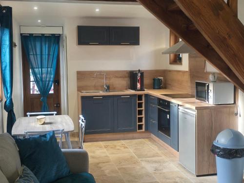 une cuisine avec des armoires bleues et un canapé dans une pièce dans l'établissement Charmante Maison au calme, à Saint-Denis-le-Ferment