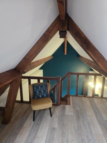 Cette chambre mansardée dispose d'une chaise et de poutres apparentes. dans l'établissement Charmante Maison au calme, à Saint-Denis-le-Ferment