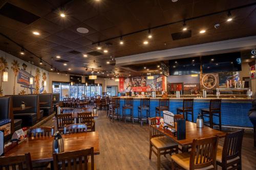 a restaurant with wooden tables and chairs and a bar at Holiday Inn Brookfield - Milwaukee by IHG in Brookfield