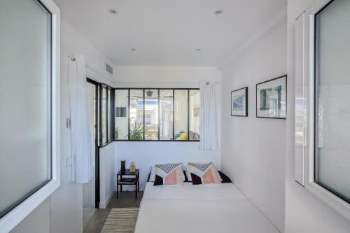 une chambre blanche avec un lit et une fenêtre dans l'établissement Centre-ville – Appartement (A/C) 6 personnes – 5 minutes plages et gare by Weekome, à Antibes