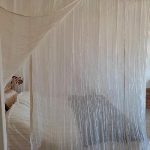 - un lit à baldaquin avec des rideaux blancs dans l'établissement La pinede a 1km de la plage, à Saint-Mandrier-sur-Mer