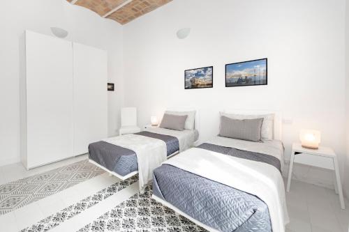 two beds in a room with white walls at Vatican White Domus in Rome