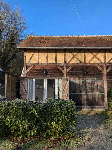a wooden barn with a window and a hedge at La sellerie - small barn in Saint-Aubin-Epinay
