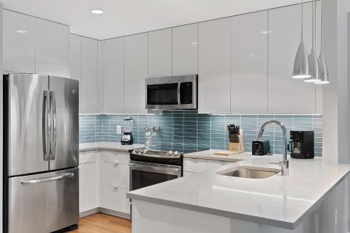 a kitchen with white cabinets and a stainless steel refrigerator at Global Luxury Suites at Brookline Village in Brookline