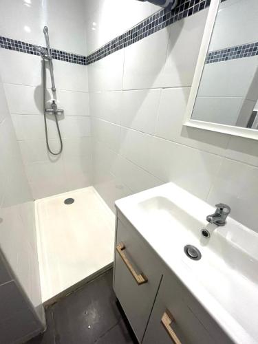 a white bathroom with a sink and a shower at Logement accueillant in Gaillon