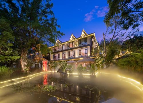 a large house with a pond in front of it at Yun Guan Shunde Renjia Resort Hotel in Jinghong