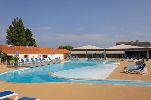 une grande piscine avec des chaises et un bâtiment dans l'établissement Camping La Pointe Saint-Gildas - Maeva, à Préfailles