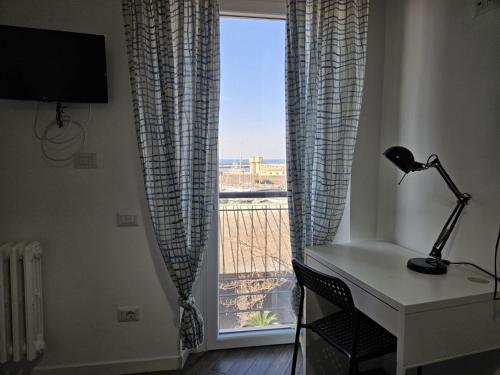 a desk with a lamp in front of a window at Be Your Home - Guest House Colors in Civitavecchia