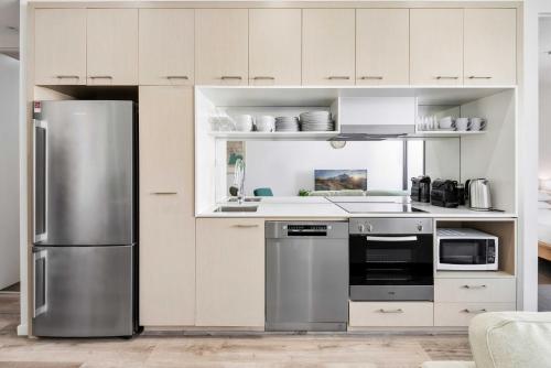 a kitchen with white cabinets and a stainless steel refrigerator at Stylish 2-Bed Apartment Near MCG in Melbourne