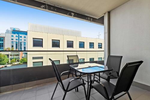 a balcony with a table and chairs and a large window at Stylish 2-Bed Apartment Near MCG in Melbourne