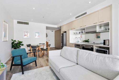 a living room with a white couch and a kitchen at Stylish 2-Bed Apartment Near MCG in Melbourne