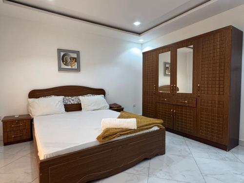 a bedroom with a bed with a wooden headboard at Résidence Cheikh Mahy Cisse Appartements, studios et chambres a louer meublé et climatisé in Kaolack