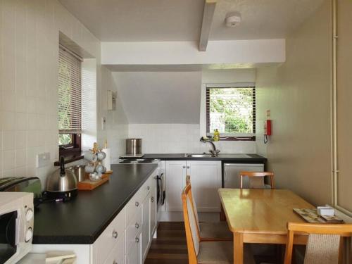 a kitchen with a black counter top and a table at Glyndley Manor Cottages in Polegate