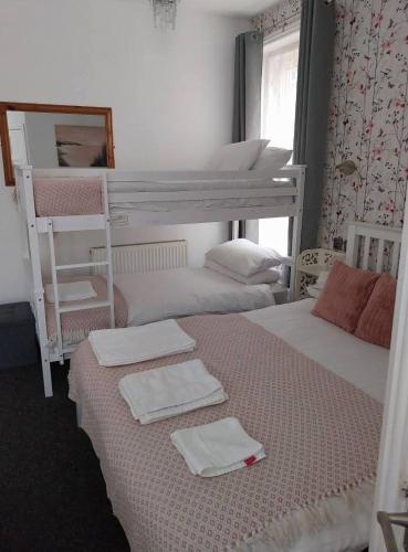 a bedroom with two bunk beds with towels and a mirror at Delamere Hotel in Blackpool