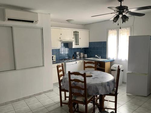 une cuisine avec une table, des chaises et un réfrigérateur dans l'établissement Appartement avec piscine partagée à Roquefort-la-Bédoule - 50m², à Roquefort-la-Bédoule