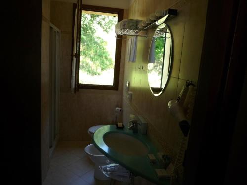 a bathroom with a green sink and a toilet at Saturnia Tuscany Country House in Saturnia
