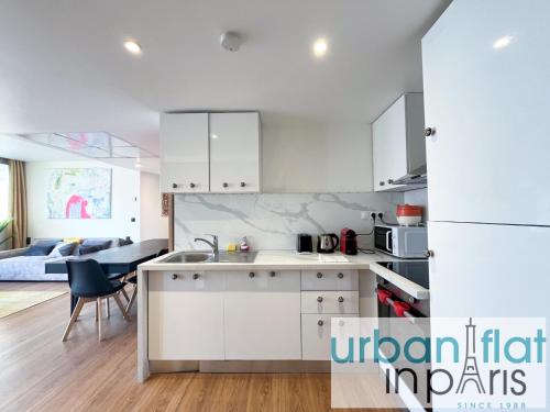 une cuisine avec des armoires blanches et un lit dans une chambre dans l'établissement Urban Flat 128 - Beautiful 4 BDR Flat Champs-Elysees, à Paris