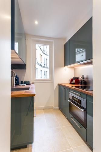 une cuisine avec des armoires vert foncé et une fenêtre dans l'établissement Montmartre Seveste Beautiful Apartment 2BR, à Paris