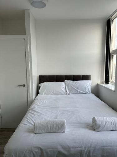 a large white bed with two towels on it at Train Station Aparthotel - Free Wifi, Free Parking in Scunthorpe