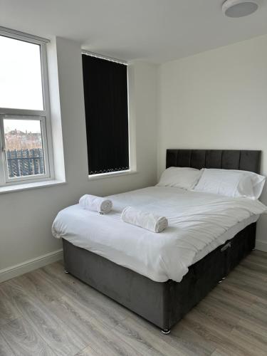 a bedroom with a large bed with two towels on it at Train Station Aparthotel - Free Wifi, Free Parking in Scunthorpe