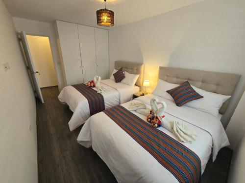 two beds in a hotel room with towels on them at Acogedor Departamento en Cusco, Ideal para Familias y Amigos, Equipado y Céntrico in Cusco