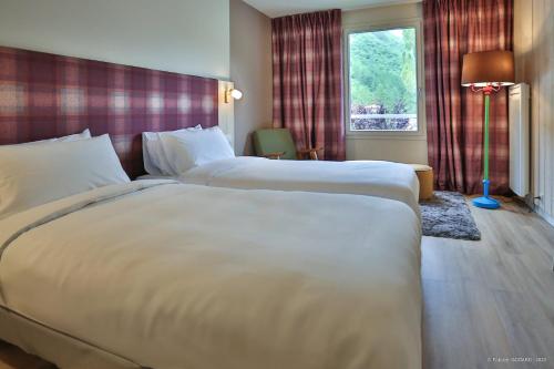 a hotel room with two beds and a window at Hôtel Le Refuge des Sources in Digne-les-Bains