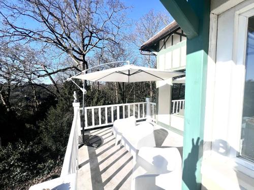 a white porch with an umbrella on a house at Enclos de Châtillon - Grand jardin dépendance in Jouy-en-Josas