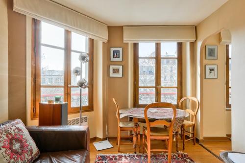 un salon avec une table, des chaises et des fenêtres dans l'établissement Lovely 1 BR near Sacré-Coeur Basilica, à Paris