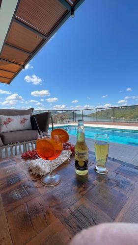 a bottle of beer and two glasses on a wooden table at Vista do Lago Hotel in Capitólio