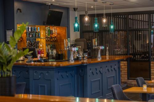 a bar in a restaurant with blue cabinets at Hotel St Pierre, Sure Hotel Collection by Best Western in Wakefield