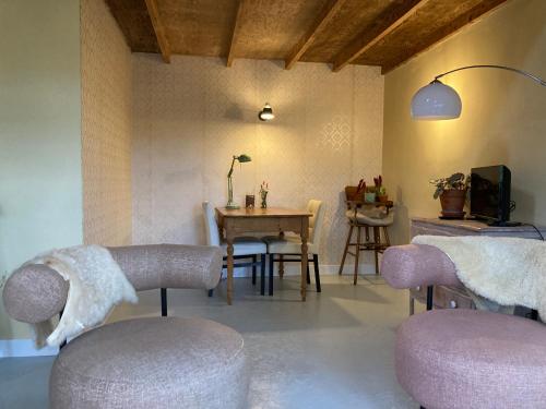 a living room with chairs and a table and a dining room at Pluk het Geluk in Laag-Soeren