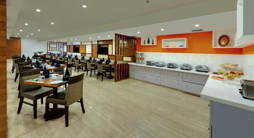 a dining room with tables and chairs and a kitchen at Best Western Alkapuri in Vadodara