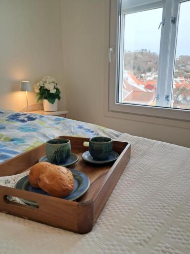 a tray with two cups and a bread on a bed at Central and spacious 3-bedroom apartment in Mandal