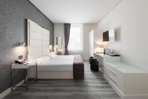 a bedroom with a large white bed and a desk at LHP Hotel Montecatini Palace & SPA in Montecatini Terme