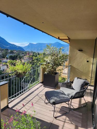 a balcony with two chairs and a view of the mountains at Levita Living Wolke in Merano