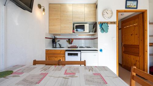 une cuisine avec une table et une horloge au mur dans l'établissement Les Eterlous N07 - 2P5, à Morillon