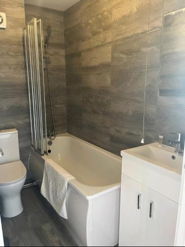a bathroom with a tub and a toilet and a sink at Spacious Townhouse in South Norwood