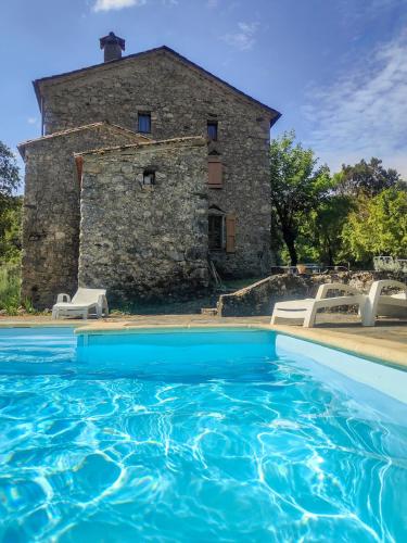 une ancienne maison en pierre avec une piscine en face de celle-ci dans l'établissement La Grossille Mas avec piscine, à Notre-Dame-de-la-Rouvière