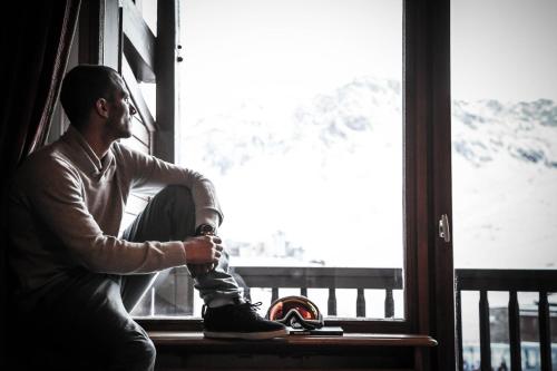 a man sitting on a window sill with his shoes on at Hôtel Le Refuge in Tignes
