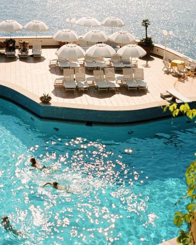 a swimming pool with chairs and umbrellas in the water at Hotel Carasco in Lipari