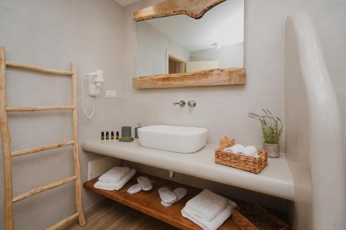 a bathroom with a sink and a mirror and towels at Onar Sifnos Stone Villa in Sifnos