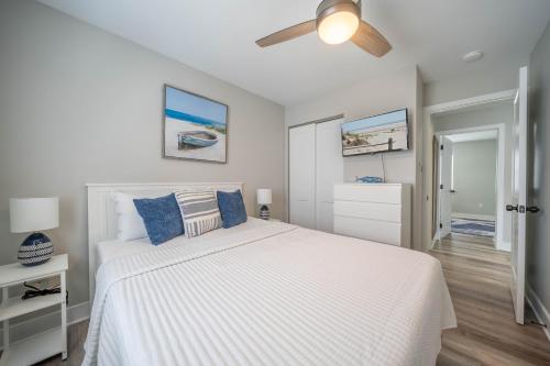 a bedroom with a white bed and a ceiling fan at Surf Shore Properties in North Wildwood