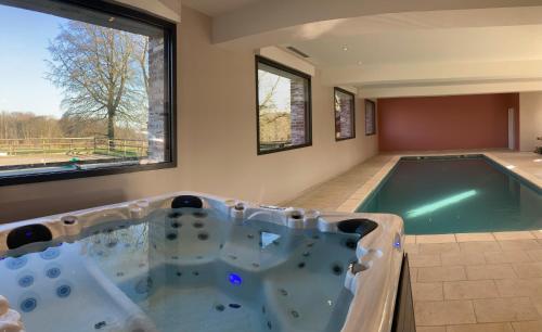 une baignoire jacuzzi dans une chambre avec fenêtres dans l'établissement La Ferme de la Forêt, gite de groupe à la campagne, à Longvilliers