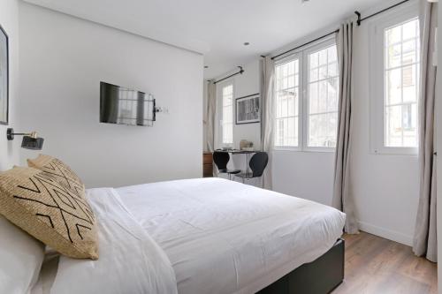 une chambre blanche avec un lit et deux fenêtres dans l'établissement TBS 308 - Beautiful studio near Marais district, à Paris