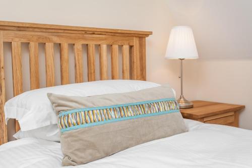 Cama con cabecero de madera y almohada en Watercress Lodges & Campsite, en New Alresford