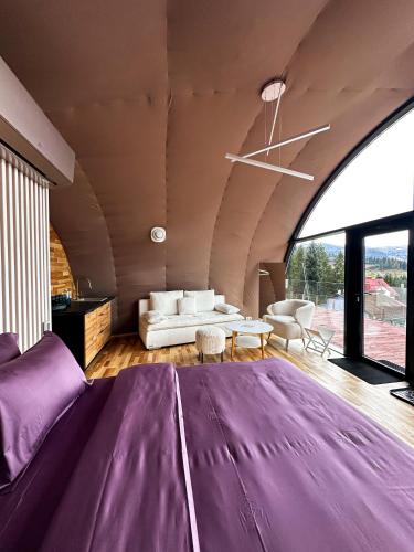 1 dormitorio con 1 cama grande de color púrpura y 1 sofá en Глемленд, en Yaremche