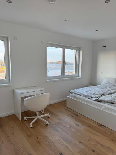 a bedroom with a bed and a desk and two windows at New & elegant penthouse apartment in Salching